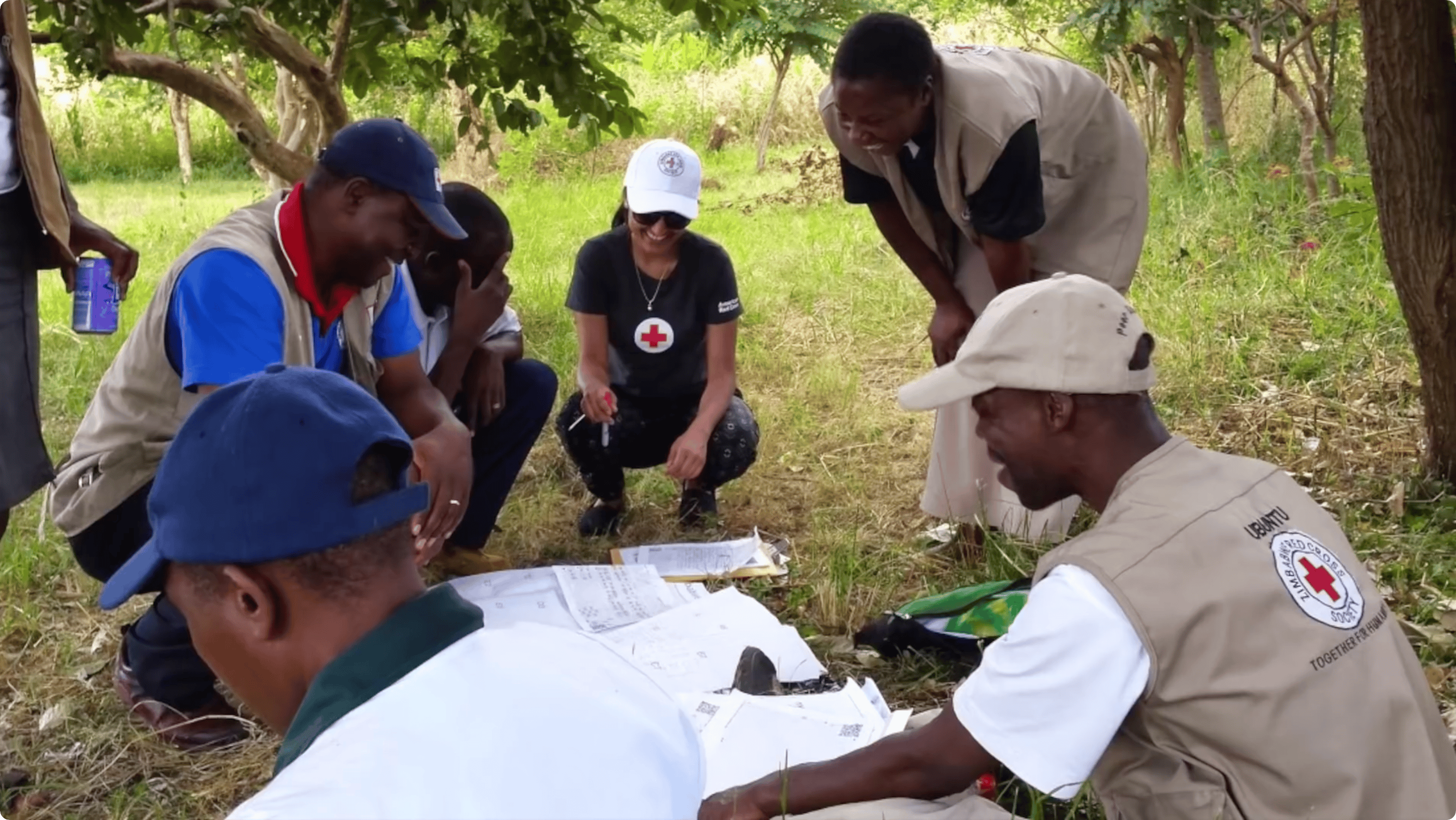 Працівники гуманітарної місії Червоного Хреста розклали на землі папери з дослідженням місцевості та обговорюють їх